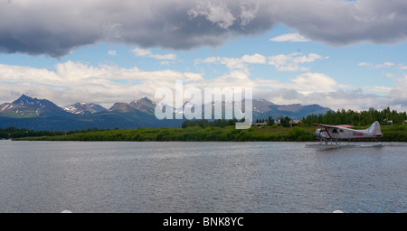 Ponton-Flugzeug fliegt von Lake Hood in Anchorage, umrahmt von den Chugach Mountains Stockfoto