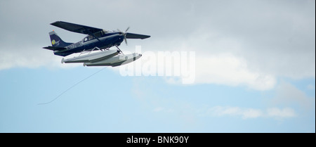 Ponton-Flugzeug fliegt von Lake Hood in Anchorage, umrahmt von den Chugach Mountains Stockfoto