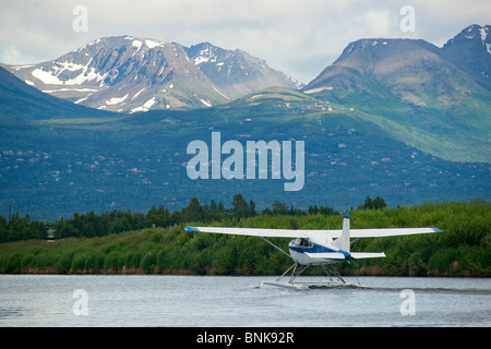 Ponton-Flugzeug fliegt von Lake Hood in Anchorage, umrahmt von den Chugach Mountains Stockfoto