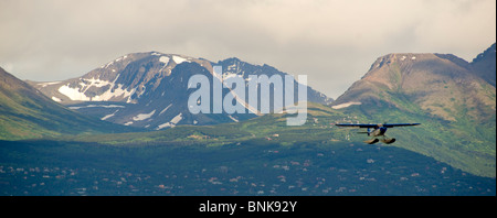 Ponton-Flugzeug fliegt von Lake Hood in Anchorage, umrahmt von den Chugach Mountains Stockfoto