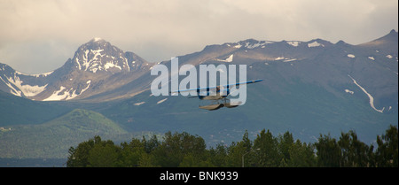 Ponton-Flugzeug fliegt von Lake Hood in Anchorage, umrahmt von den Chugach Mountains Stockfoto