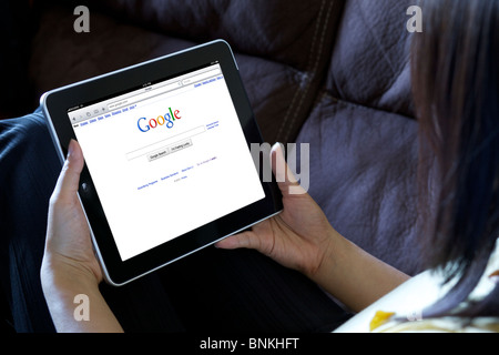 Eine Frau und zeigt Google Bildschirm-Seite von einem iPad gleichzeitig entspannend Stockfoto
