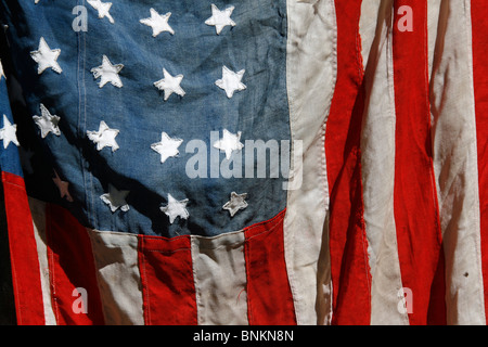 eine alte amerikanische Flagge an Wand draußen in der Sonne hängen Stockfoto