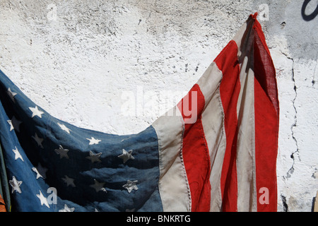 eine alte amerikanische Flagge an Wand draußen in der Sonne hängen Stockfoto