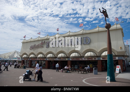 Eine Familie mit einem Kind im Kinderwagen spazieren gehen vor Funland Arcade auf der Promenade am Southport England Stockfoto