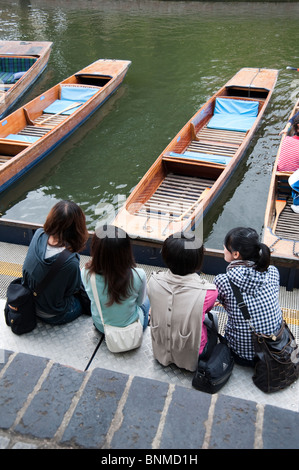 Japanische Touristen sitzen auf dem Kai, die darauf warten, auf dem Fluss Cam, Cambridge Stechkahn fahren gehen Stockfoto