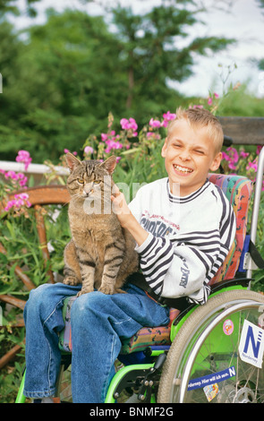 Behinderte Junge im Rollstuhl, Streicheln einer Katze Stockfoto