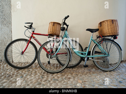Zwei Fahrräder parken gegen eine Wand in einer gepflasterten Straße in Vigevano, Italien Stockfoto