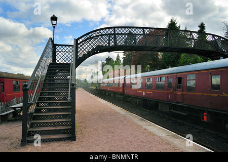 Dampfmaschine / Lokomotive mit roten Wagen bei Boat of Garten Railway Station, Schottland, UK Stockfoto