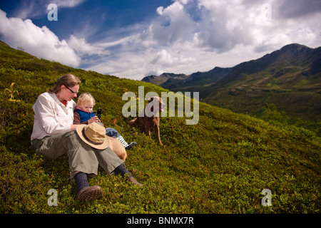 Mutter und Tochter sitzen auf einem Hügel sprechen auf einem Handy, Hatcher Pass, Alaska Stockfoto