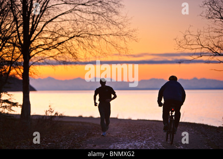 Menschen genießen die Tony Knowles Coastal Trail bei Sonnenuntergang mit der Alaskakette im Hintergrund, Anchorage, Alaska Stockfoto