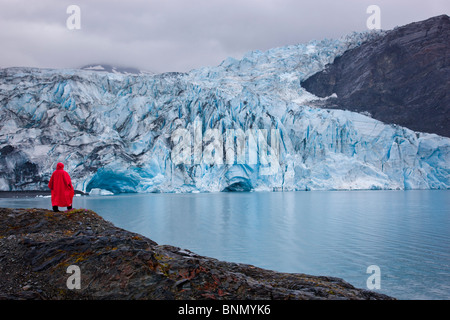 Person in einem roten Poncho steht auf einer Insel vor Shoup Gletscher, Shoup Bay State Marine Park, Alaska Stockfoto