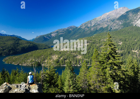 Frau sitzt Rock Ross Lake Marblemount North Cascades National Park Washington USA Bäume Berge Stockfoto