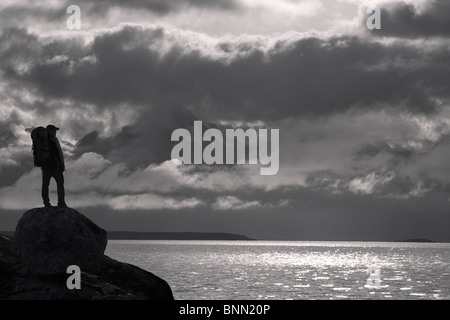 Zusammensetzung: Silhouette ein Wanderer entlang der Ufer des Lynn Canal mit Chilkat Bergen im Hintergrund, Inside Passage, Alaska Stockfoto
