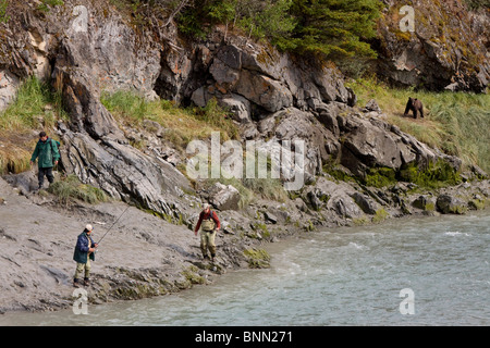 Drei Fischer verlassen die Ufern des Bird Creek als ein Braunbär Ansätze entlang der Küstenlinie, Alaska Stockfoto