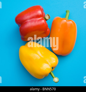 Orange; rote und gelbe Paprika auf leuchtend blauen Kunststoff Schneidebrett; Stockfoto