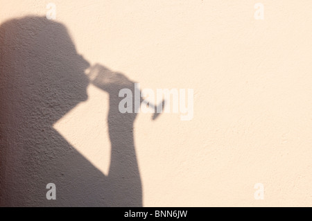 Schatten Sie auf eine strukturierte Wand einer Frau trinken ein Glas Wein Stockfoto