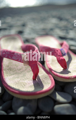 Ein paar rosa Flip flops Schuhe auf einem Kieselstrand, Sommer UK Stockfoto