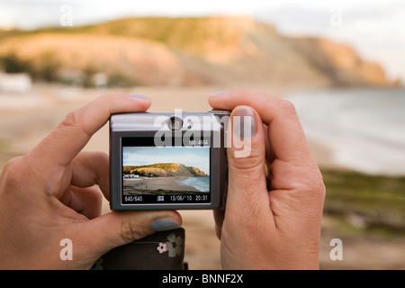 Eine weibliche Urlauber fotografiert ein Rocha Negra Klippen im Luz in Lagos an der Algarve Küste von Portugal. Stockfoto