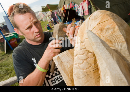 Glastonbury Festival. Bildhauer im Bereich Green Fields des Festivals auf eine hölzerne Skulptur arbeiten. Stockfoto