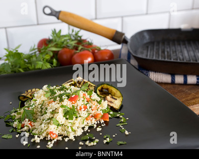 Couscous-Salat auf einem dunklen grauen Teller. Stockfoto