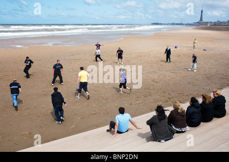 Eine Gruppe von Menschen spielt ein Fußballspiel am Strand in Blackpool, England. Stockfoto