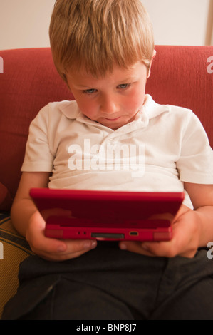 Ein MODEL-Release Nahaufnahme Bild eines sechsjährigen Jungen spielen auf einem Nintendo DS handheld Computer Spielkonsole im Vereinigten Königreich Stockfoto