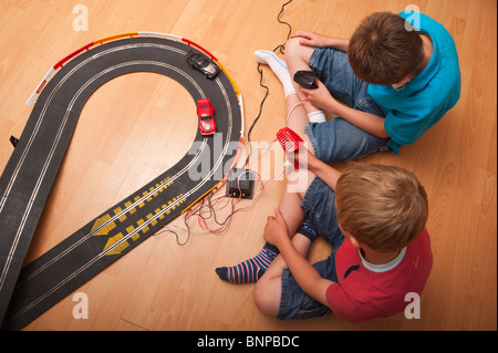 Ein MODEL Release Bild von zwei jungen setzen (6 & 10) spielen mit einem Hornby Scalextric Rennwagen Spiel im Vereinigten Königreich Stockfoto