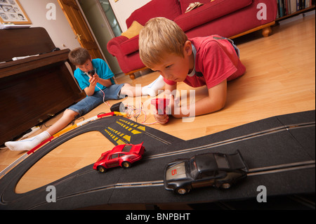 Ein MODEL Release Bild von zwei jungen setzen (6 & 10) spielen mit einem Hornby Scalextric Rennwagen Spiel im Vereinigten Königreich Stockfoto