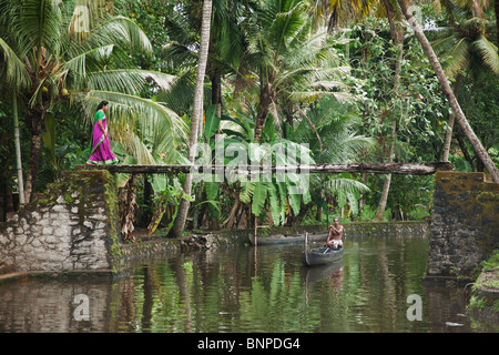 Frau mit hell lila und grüne Sari zu Fuß über einen schönen malerischen Kanalbrücke in Alappuzha, Kerala, Indien. Modell veröffentlicht Stockfoto