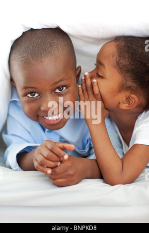 Entzückende kleine Mädchen flüsterte etwas zu ihrem Bruder Stockfoto