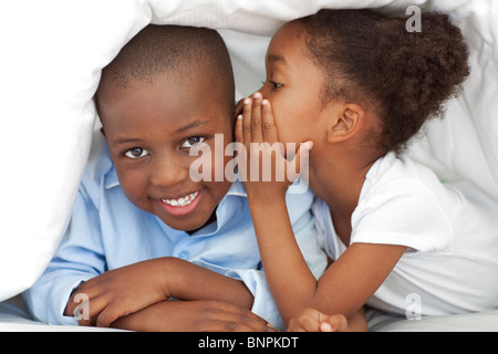 Niedliche kleine Mädchen flüsterte etwas zu ihrem Bruder Stockfoto