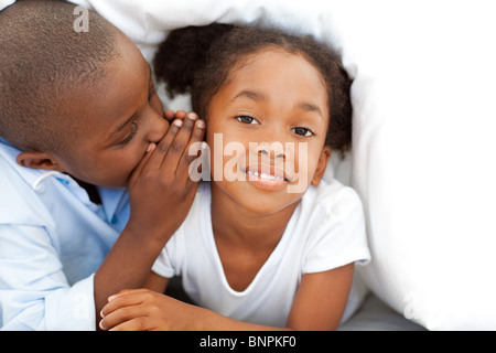 Entzückende kleine Junge flüstert etwas an seine Schwester Stockfoto