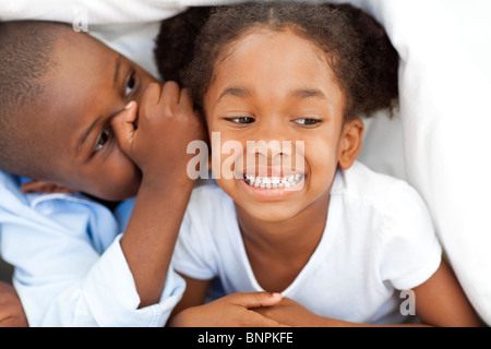 Kleiner Junge flüstert etwas an seine Schwester Stockfoto