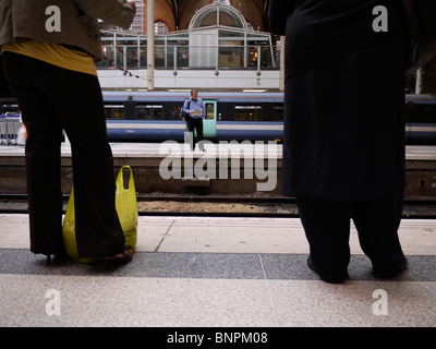 Bahnpassagiere warten auf dem Bahnsteig der Liverpool Street Station, einem der verkehrsreichsten Verkehrsknotenpunkte Londons Stockfoto