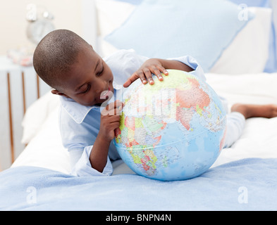 Kleiner Junge Blick auf einem Globus Stockfoto