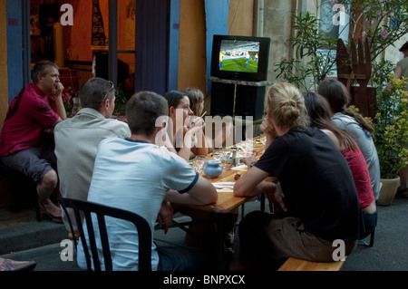 Arles, Frankreich, Leute auf der Terrasse des Bistro-Restaurants der französischen Provinz, Drinks teilen, Fußballspiele bei T.V.group Freunden in der Ferienstadt [Rear] anschauen, die raucht Stockfoto