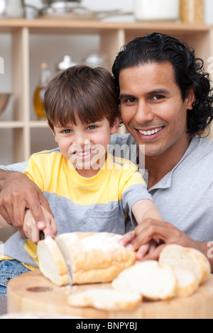 Lächelnden Vater helfen, seinem Sohn etwas Brot geschnitten Stockfoto