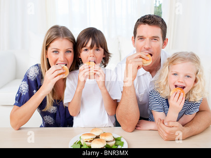Hungrige Familie essen Burger im Wohnzimmer Stockfoto