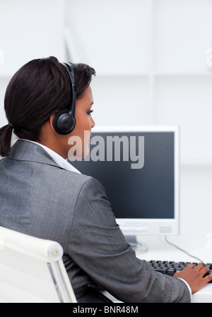 Ernsthafte Geschäftsfrau, die Arbeit am Computer mit Kopfhörer auf Stockfoto