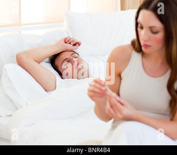 Betroffenen Frau, die ihrem kranken Ehemann Temperatur Stockfoto