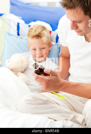 Charmante Vater seinen kranken Sohn Hustensaft geben Stockfoto