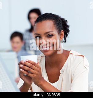 Glühende Geschäftsfrau Kaffeetrinken an ihrem Schreibtisch Stockfoto