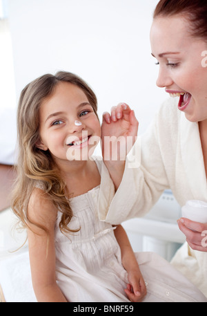 Glückliche Mutter ihre Tochter Gesicht Creme aufsetzen Stockfoto