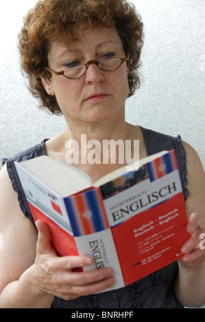 Frau betrachten Deutsch Englisch Wörterbuch von Wörterbuch veröffentlicht Stockfoto