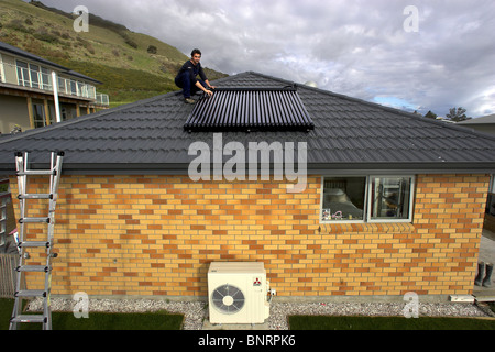 Qualifizierte Handwerker, die Installation von solar-Warmwasser-System zu einem Haus, Nelson, New Zealand, die Stadt mit der höchsten Sonnenscheinstunden Stockfoto