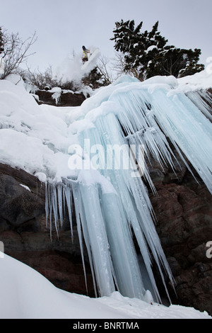 Ein Snowboarder springt von einem Eis Wasserfall Klippe zu Pulver in Colorado. Stockfoto