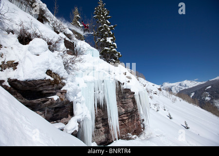 Ein Snowboarder springt von einem Eis Wasserfall Klippe zu Pulver in Colorado. Stockfoto