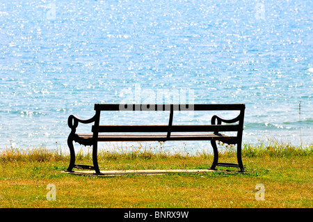 Leere Bank auf Rasen Klippe mit Meer im Hintergrund Stockfoto