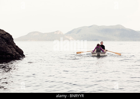 Ein junges Paar Zeile in den Puget Sound von Orcas Island in einem kleinen Ruderboot. Stockfoto